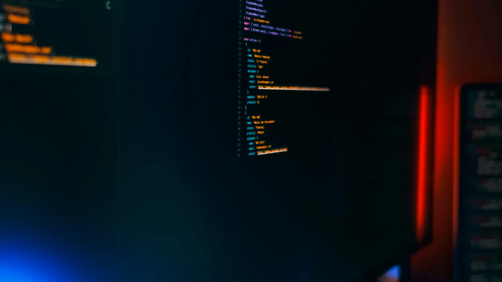 Lines of code on a dark monitor lit by blue and red light
